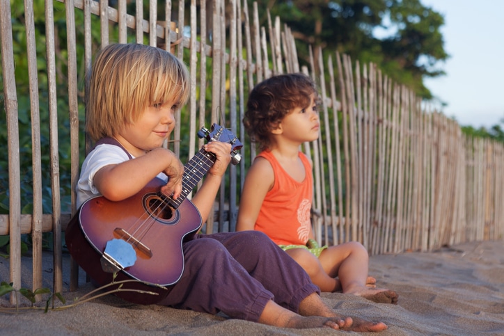 Kinder am Strand mit Gitarre