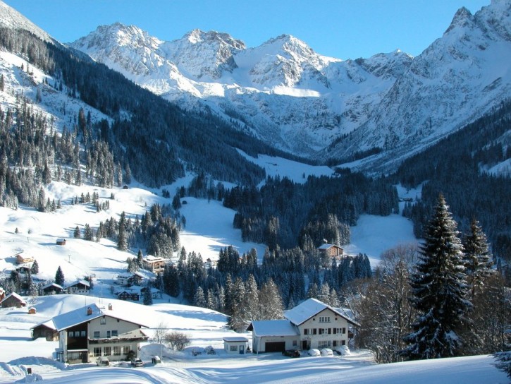 Das Ferienhaus Ahorn (vorne rechts) in Mittelberg empfängt bis zu 20 Personen im Herzen des Allgäuer Winterwunderlands.