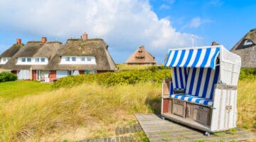 Beach chair on sand dune and typical cottages in List village, Sylt island, Germany
