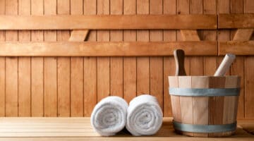 Wooden bucket and white rolled towels in a sauna