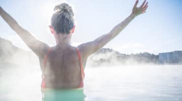 Woman relaxing arms outstretched in hot spring pool in Iceland.