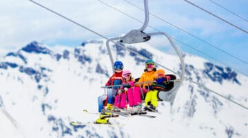 Family in ski lift in mountains. Skiing with kids