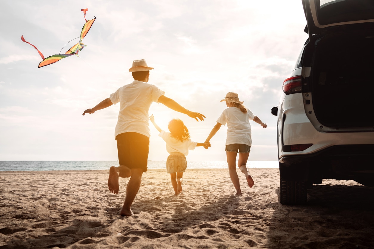 Familie am Strand mit Auto und Kindern, Last-Minute-Urlaub am Strand