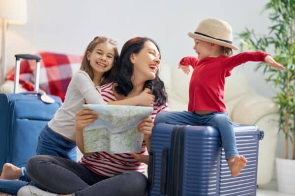 Frau mit Kinder packt Koffer für die Reise in eins der beliebtesten Urlaubsländer
