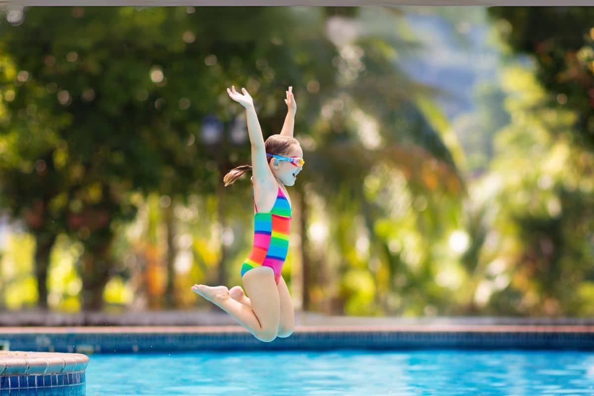 Kind springt im Freibad ins Wasser