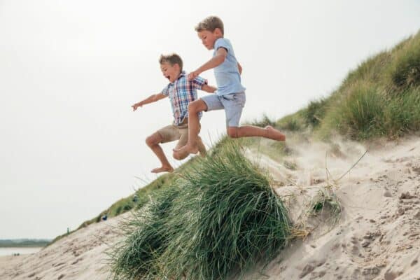 Kinder springen in Amrum über Dünen