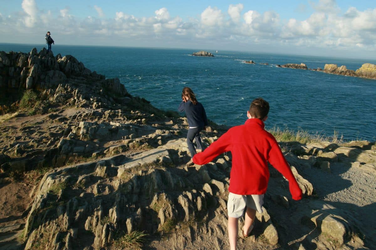Kinder laufen auf Steinen an der Französischen Atlantikküste entlang