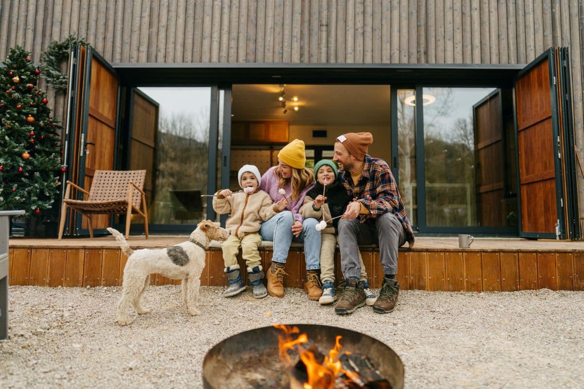 Familie mit Hund sitzt vor ihrem Ferienhaus beim lange reisen