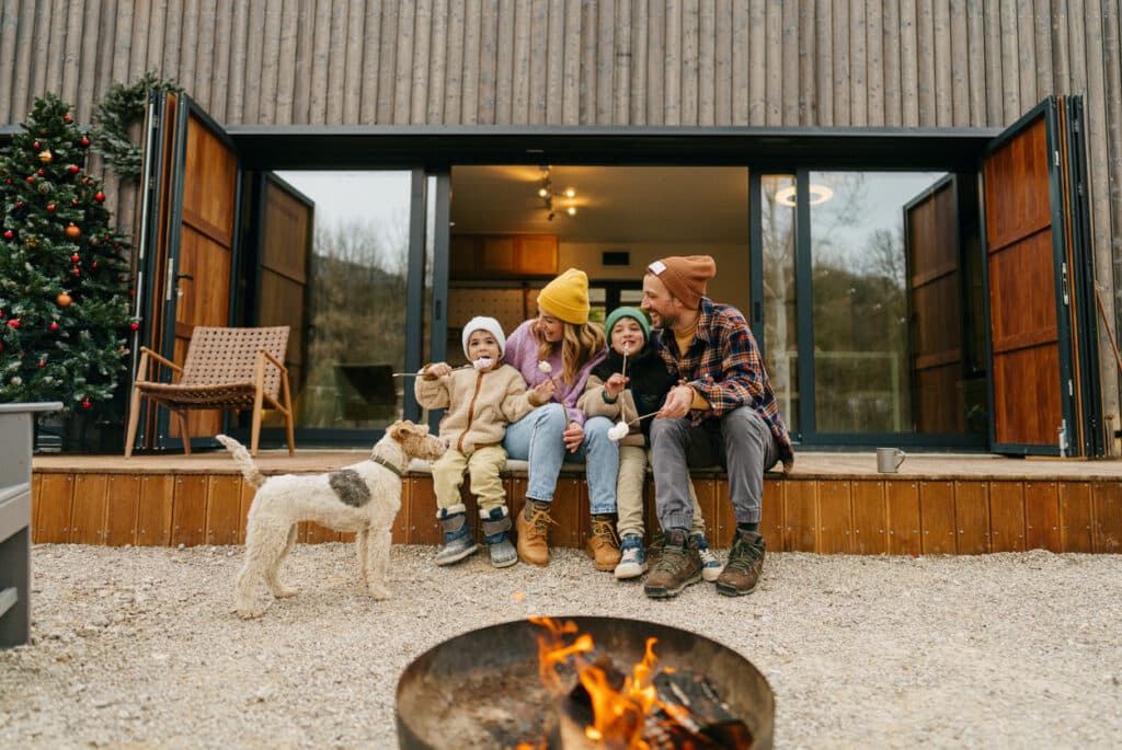 Gemütliches Beisammensitzen einer Familie mit 2 Kindern und Hund im Außenbereich des privaten Ferienhauses bei Urlaub in den Bergen